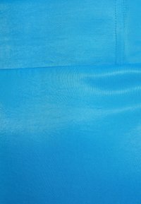 Tissu bleu vif avec une texture lisse, présentant de subtiles variations de teinte et une couture plate le long du bord supérieur.