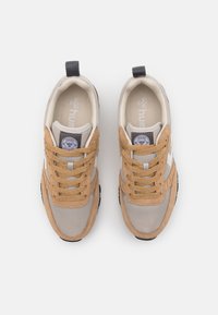 Pari bežin və qəhvəyi çəkmələr, qəhvəyi ip ilə və qara çəkici ilə, ağ fonda yuxarıdan baxışla.