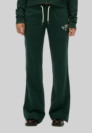 Groene joggingbroek met een uitlopende pasvorm, een trekkoord in de taille en witte logotekst op het linkerbeen. Zacht materiaal met een gladde textuur.