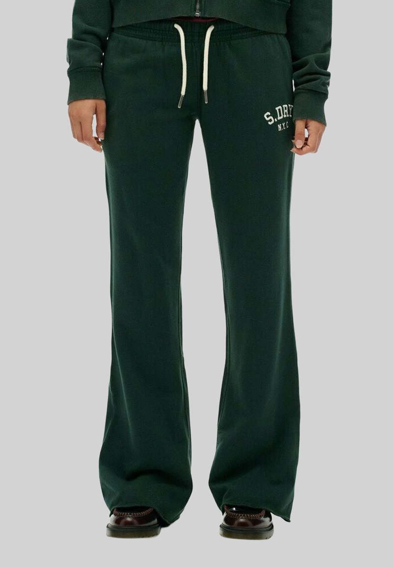 Pantalons de jogging verts avec un design évasé, une taille à cordon et un texte logo blanc sur la jambe gauche. Tissu doux avec une texture lisse.