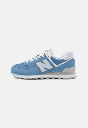 Blauwe sportieve schoen van suede met witte accenten, meshpanelen en een dikke rubberen zool. Voorzien van het kenmerkende "N"-logo en een gestructureerd oppervlak.