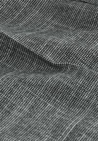 Černobrázková texturovaná tkanina s vzorem houndstooth, která vykazuje jemný, tkaný vzhled s různými odstíny šedé.