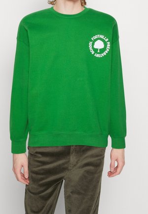 Sweat-shirt en coton vert à manches longues, col ras du cou, avec un logo d'arbre blanc et du texte sur la poitrine gauche. Texture douce, coupe ample.