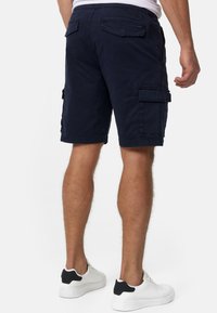 Marineblå cargoshorts i bomuldsblanding med flere sidelommer, en baglomme med klapper og en afslappet pasform. Bruges med hvide sneakers.