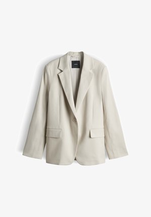 Blazer beige à un bouton avec revers crantés, deux poches avant à rabat, manches longues et une étiquette intérieure noire.