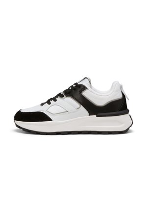 Baskets de sport noires et blanches avec une tige en cuir texturé, des superpositions contrastantes, une semelle épaisse et des lacets noirs. Détail mineur d'une languette à l'arrière.