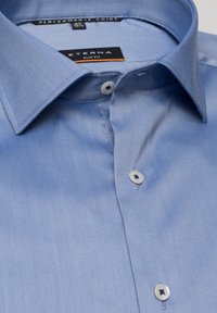 Camicia da uomo slim fit azzurro chiaro con colletto a punta e bottoni bianchi, con etichetta "Eterna" e "Performance Shirt" all'interno del colletto.