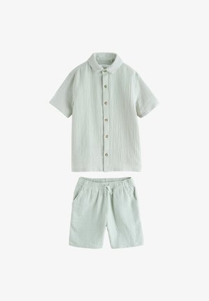 Hellgrünes kurzärmeliges Hemd zum Knöpfen mit elastischen Taillenshorts, beide aus strukturiertem, leichtem Stoff mit dezenten vertikalen Linien.