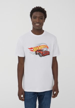 T-shirt bianca in cotone con una grafica colorata "Hot Wheels" che presenta una macchina rossa e un design di fiamme sul petto. Maniche corte, collo a giro.