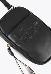 Crna kožna torba preko tijela s utisnutim logom. Ima zaobljen oblik, zlatne detalje i uzorčenu naramenicu. Glatka tekstura.