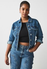 Denim jacket featuring a classic collar, button closure, and two chest pockets, paired with high-waisted denim pants in a matching blue hue.