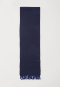 Mørkeblå vævet tørklæde med et fiskebensmønster, afsluttet med frynser i kanterne og et lille logo-tag i den ene ende.
