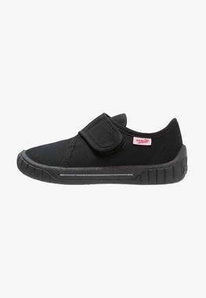 Chaussure basse noire avec bride velcro, semelle souple texturée et petite étiquette rose "superfit" sur le côté, conçue pour un port facile.