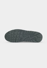 Σόλα σκούρου γκρι αθλητικού παπουτσιού Nike με υφή πέλματος που περιλαμβάνει τετράγωνα και ορθογώνια σχέδια και το λογότυπο της Nike κοντά στην καμάρα.