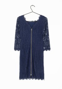 Mörkblå spetsklänning med scallop-kantad halsringning och korta ärmar. Har en central dragkedja med dekorativa spetskanter vid nederdelen.