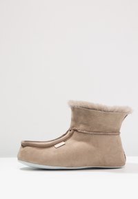 Brown suede boot with a soft, fuzzy top edge and a rounded toe. Features contrasting stitching and an inner lining for comfort.