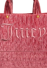 Czerwona torba tote z teksturą, o pomarszczonej, aksamitnej powierzchni, z haftowanym logo "Juicy" i mosiężnymi akcentami.