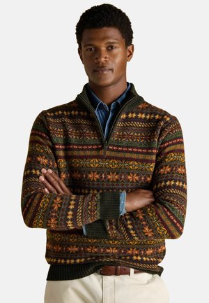 Strickpullover mit Reißverschlusskragen, der reichhaltige mehrfarbige Muster in Grün, Orange und Braun zeigt. Rippbündchen und Saum, über einem Denim-Hemd getragen.