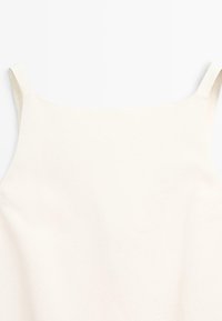 Cremfarbens Spaghettiträgershirt mit dünnen Trägern, glatter Textur und minimalistischem Design, das keine Muster oder zusätzlichen Akzente aufweist.