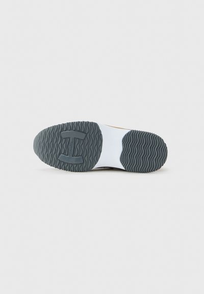 Shoe sole with black and white rubber tread, featuring a wave pattern and a block-shaped grip section in the middle.