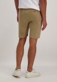 Khaki shorts van een zachte, textuurstof met een achterzak en een middelhoge taille. Draag ze met witte sneakers voor een casual uitstraling.