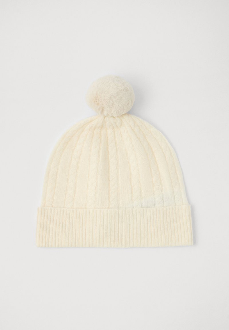 Gorro de malha em cor creme com padrão de cabo e canelado, e um pom-pom de pele no topo. Textura suave, adequado para tempo frio.