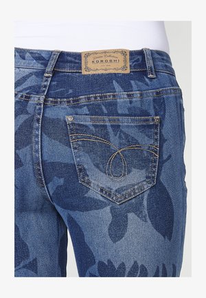 Džíny z denimu v středně modrém odstínu s květinovým vzorem. Mají výrazný design zadní kapsy a značkovou koženou nášivku nad pasem.