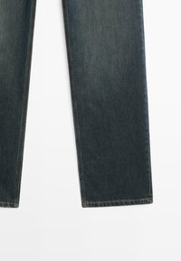 Jeans dritti blu scuro con cuciture laterali visibili distesi su uno sfondo bianco.