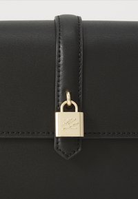 Black leather handbag with a smooth texture, featuring a gold padlock closure and stitched accents along the edges. Compact rectangular shape.