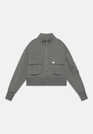 Sweat-shirt gris court avec un col haut, une fermeture éclair sur le devant et deux grandes poches à rabat sur la poitrine. Tissu doux et texturé avec des manches à poignets.