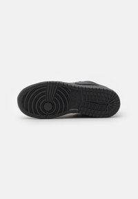 Schwarze Sneaker-Sohle mit kreisförmigen und gerillten Texturmuster, die ein zentrales kreisförmiges Emblem und eine mehrlagige Gummikonstruktion aufweist.