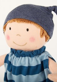 Weiche Stoffpuppe mit einem lächelnden Gesicht, die einen dunkelblauen Strickhut und ein gestreiftes blaues und hellblaues Kleid mit gerafftem Halsausschnitt trägt.