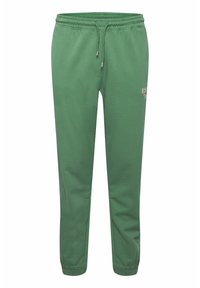Grønne joggesbukser laget av myk stoff, med elastisk midjebånd og snøring, smalnede ben og en liten trykket logo på siden.