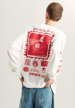 Langærmet hvid skjorte med røde grafiske tryk, herunder logoer og et skaterdesign på ryggen og ærmerne, afslappet pasform og lavet af bomuldsmateriale.