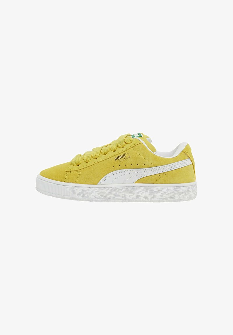 Baskets en daim jaune avec des accents blancs et une semelle en caoutchouc texturée. Présente un bout rond, des lacets plats et une petite étiquette de logo verte sur la languette.