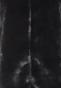 Měkká černá lesklá tkanina z umělé kožešiny s jemnými odrazy světla a svislým švem uprostřed.