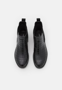 Bottines noires à motif crocodile brillant, avec des panneaux latéraux élastiques et une semelle lisse. Texture douce et design à bout arrondi.