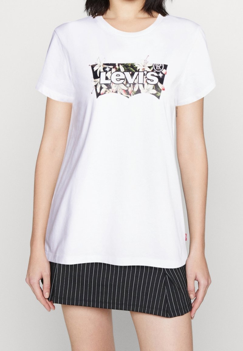 Bílá bavlněná tričko s černým a květinovým logem Levi's. Tričko má kulatý výstřih a krátké rukávy, vystavené s pruhovanou sukní.