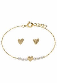 Bracelet doré avec un pendentif en forme de cœur, entrecoupé de perles blanches. Boucles d'oreilles en forme de cœur assorties avec un design texturé et nervuré en or.