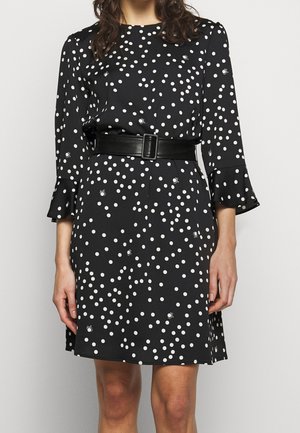 Robe noire à pois blancs avec petits motifs d'araignées, dotée d'une ceinture noire et de manches trois-quarts à poignets évasés.
