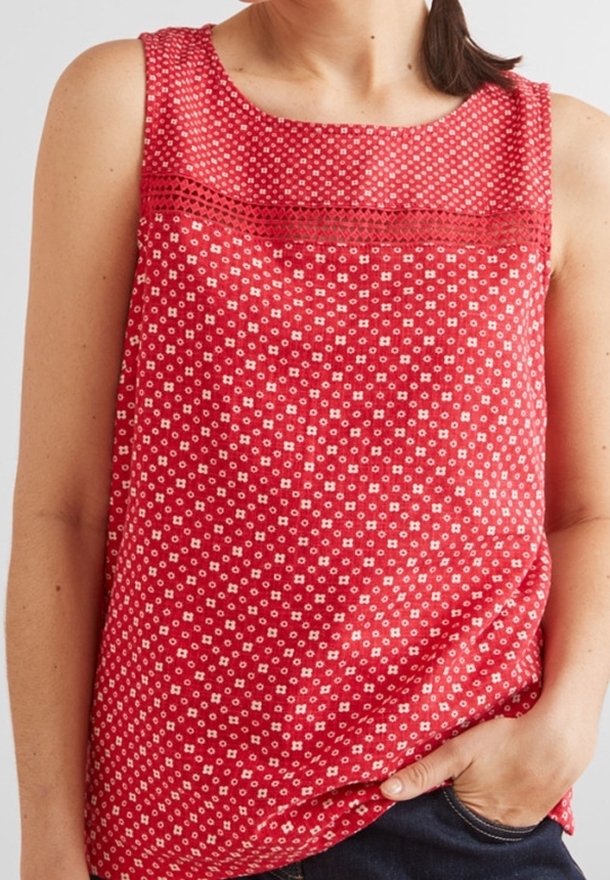 Haut sans manches rouge avec un motif floral, présentant un col bordé de dentelle et une coupe décontractée. Fabriqué en tissu léger.