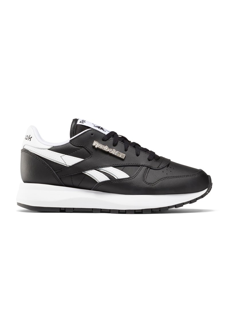 Czarne skórzane sneakersy z białymi akcentami, posiadające wyściełany kołnierz, perforowaną część przednią oraz teksturowaną gumową podeszwę. Logo Reebok jest metaliczne.