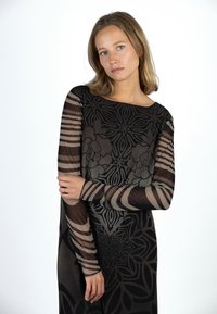 Durchscheinendes schwarzes Kleid mit floralem und geometrischem Muster. Lange Ärmel mit gestreiften Akzenten. Glatte Textur, lockere Passform, runder Ausschnitt.