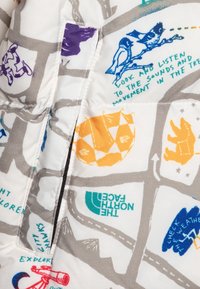 Dunjacka med vitt tyg och färgglada grafik, inklusive naturmotiv och mönster. Visningen innehåller orange, lila och blå accenter.