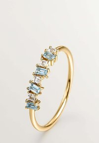 Anillo de banda de oro con gemas rectangulares alternando entre azul claro y transparentes, engastadas en garras, con un acabado suave y pulido.