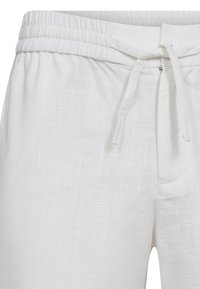 Pantaloni bianchi in lino con vita elastica e cordoncino, caratterizzati da una superficie texturizzata e tasche laterali.