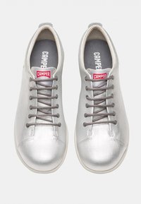 Silvriga snörskor med en texturerad yta, utrustade med grå snören, en vit gummisula och en logotab på plösen.