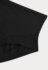 Top in tessuto elasticizzato nero con texture liscia, caratterizzato da un orlo arrotondato e cuciture piatte per un design aerodinamico.