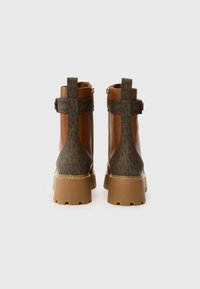Botas de tobillo de cuero marrón con acentos de textil estampado, tacones gruesos, cremalleras laterales y detalles de correas. Acabado texturizado y diseño de suela resistente.