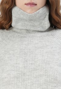 Light grey knitted turtleneck sweater with a ribbed texture and high collar, featuring a soft, slightly fuzzy finish.